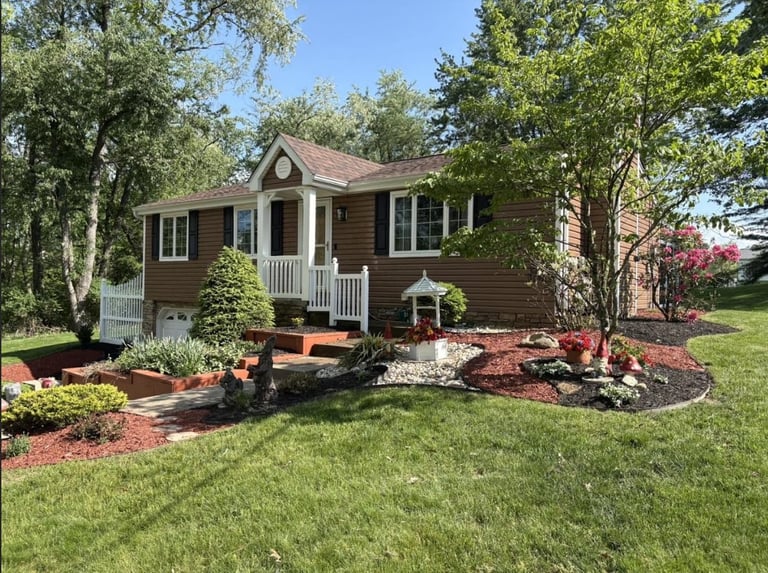 House surrounded by landscaped gardens with red mulch and flowering shrubs